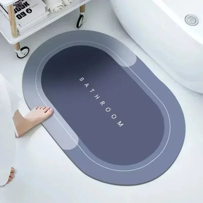An absorbent shower bath mat in gray color placed on a bathroom floor, with the word 'BATHROOM' printed in the center.